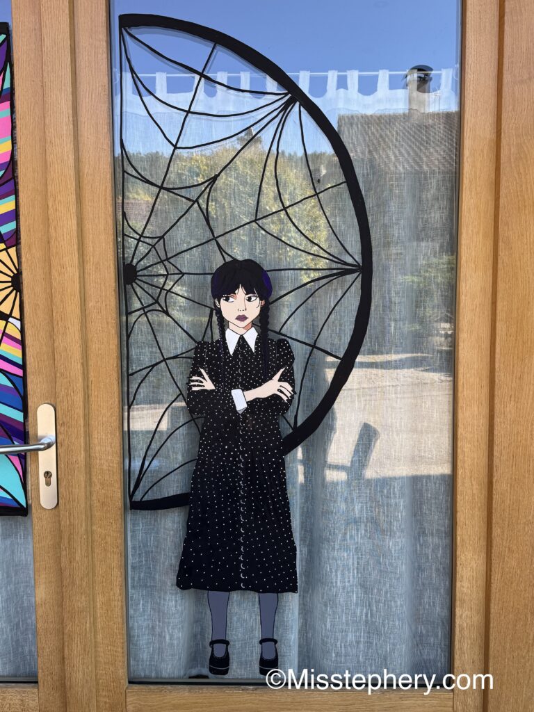 Décoration Halloween au Posca sur vitre représentant Mercredi Addams devant la fenêtre de Nevermore