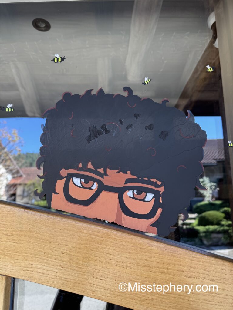 Dessin sur vitre au feutre Posca d'Eugene Otinger avec ses lunettes et entouré d'abeilles.