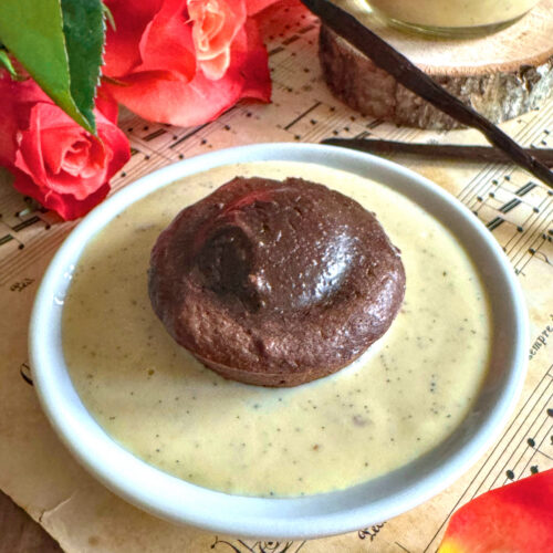 Fondant au chocolat et noisette sans beurre avec son cœur coulant, servi dans une assiette de crème anglaise vanillée à la noix de cajou.