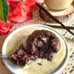 Fondant au chocolat et noisette sans beurre avec son cœur coulant, servi dans une assiette de crème anglaise vanillée à la noix de cajou.