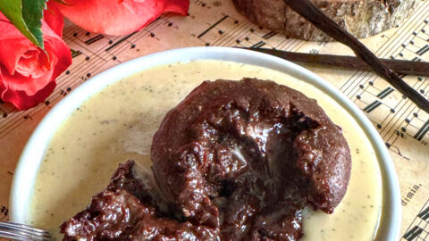 Fondant au chocolat et noisette sans beurre avec son cœur coulant, servi dans une assiette de crème anglaise vanillée à la noix de cajou.