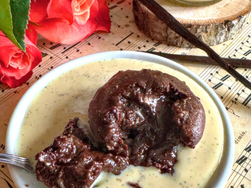 Fondant au chocolat et noisette sans beurre avec son cœur coulant, servi dans une assiette de crème anglaise vanillée à la noix de cajou.
