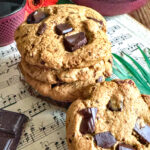 Cookies au miso et pépites de chocolat noir sans gluten et sans lactose, présentés sur une partition de musique à côté d'une théière en fonte.