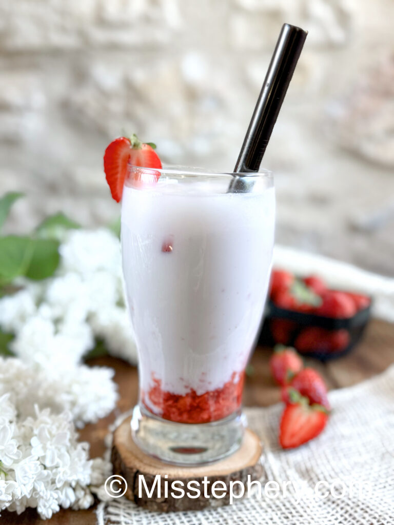 Ddalgi Latte Vegan aux fraises fraîches et lait de cajou sans lactose présenté dans un verre tulipe sur un rondin de bois.