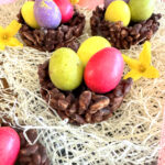 Nids de Pâques façon rose des sables au riz soufflé & chocolat (sans gluten ni lactose) avec des oeufs de dinosaure de la marque PECOU à l'intérieur. posé sur du Raphia