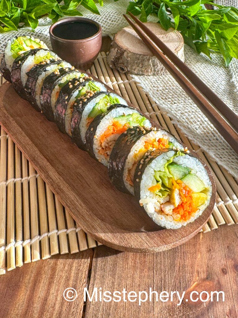 Kimbap au poulet gochujang et légumes frais sans gluten sur un plateau en bois.